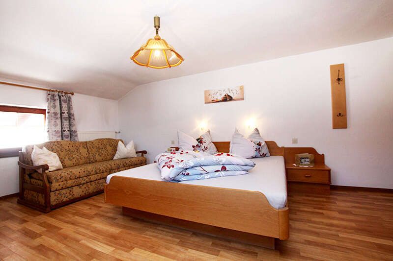 Family room with double bed and couch at the Pfandlhof